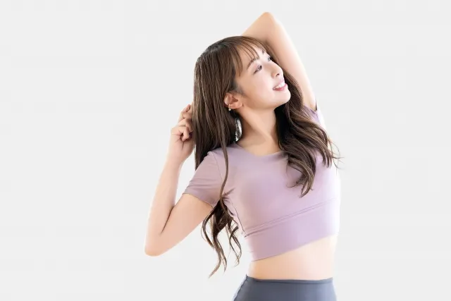 ピラティスのストレッチをしている紫色のウェアを着た髪の長い女性