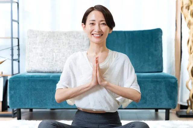 自宅でピラティスのストレッチで両掌を合わせている女性