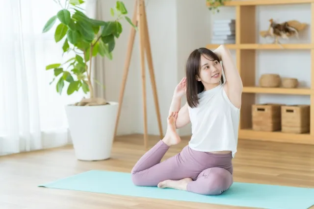 自宅の部屋でヨガの鳩のポーズをする女性