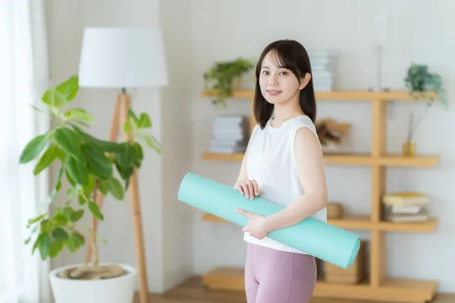 自宅でヨガマットを持ち上げている女性