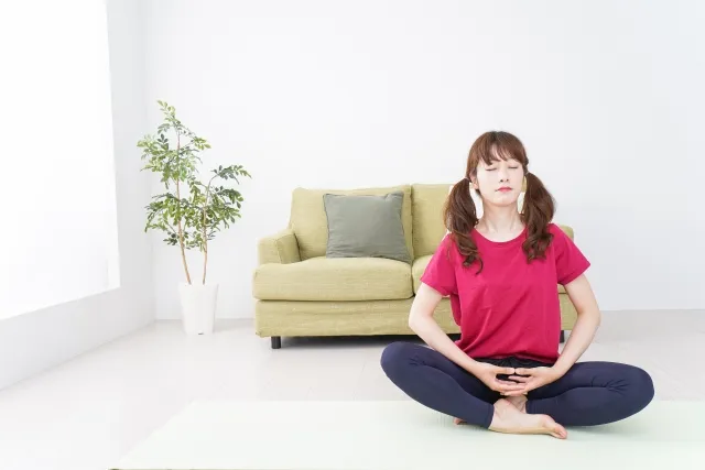 自宅でヨガの瞑想をしている赤いウェアの女性