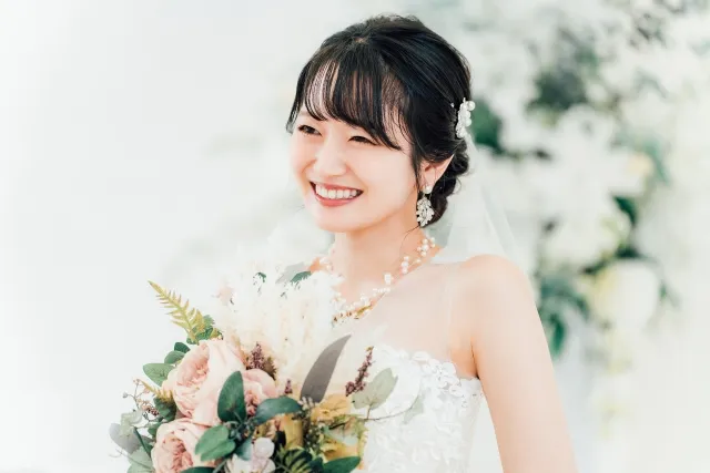 結婚式でブーケを持って微笑むウエディングドレスを着た花嫁