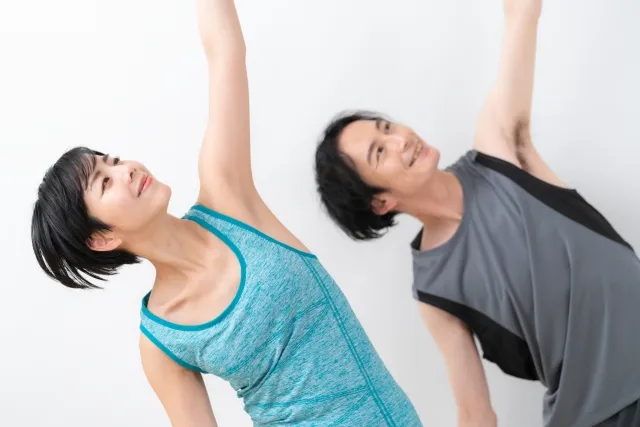 三角のポーズをしているショートカットの女性と髪の長い男性