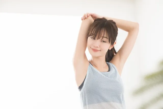 右手を頭の後ろに回し左手で右手の肘を抑えてストレッチしている女性