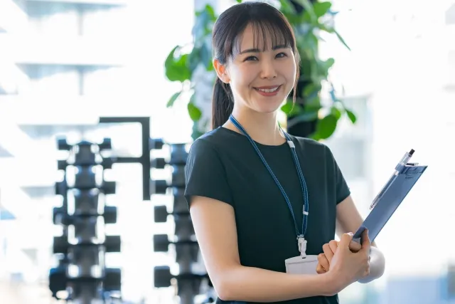 バインダーを持ち微笑んでいるインストラクターの女性