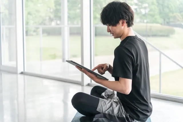 タブレットを操作してオンライントレーニングをしようとしている男性