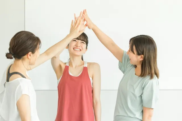 右手を上げて三人で手を合わせる女性3人