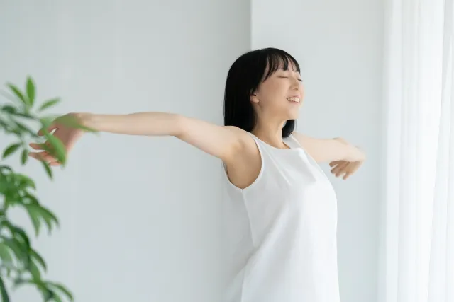 白いウェアを着た女性が両手を後方に広げてストレッチしている様子