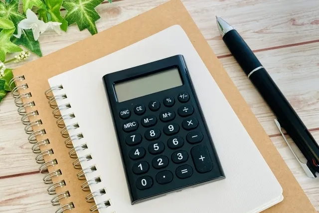 ノートの上に黒色の電卓が置かれている