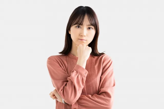右手の拳を顎に当てて考えている表情の女性